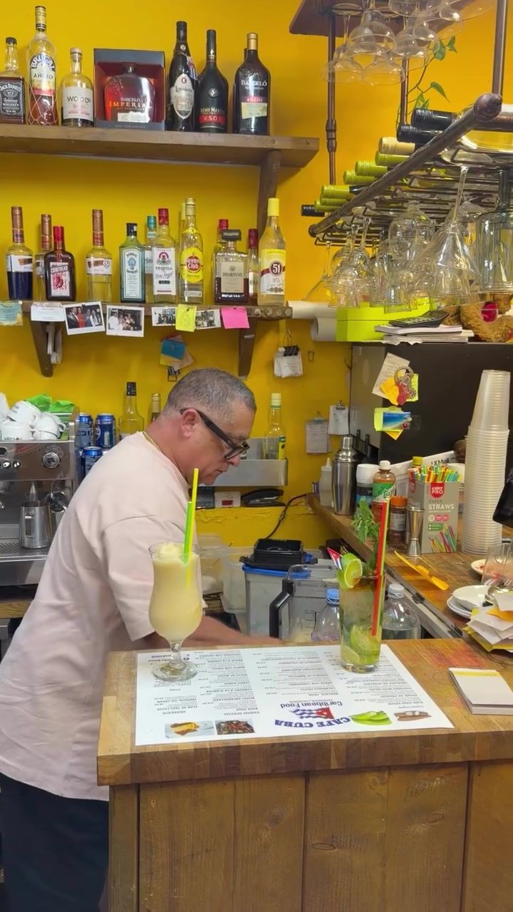 The bartender topping a piña colada at the yellow bar