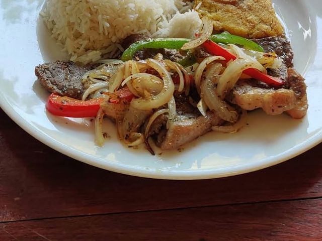 Bistec encebollado with onions and peppers, rice and tostones