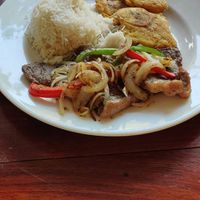Bistec encebollado with onions and peppers, rice and tostones