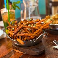 Sweet potato fries in a steel bowl, mojitos behind