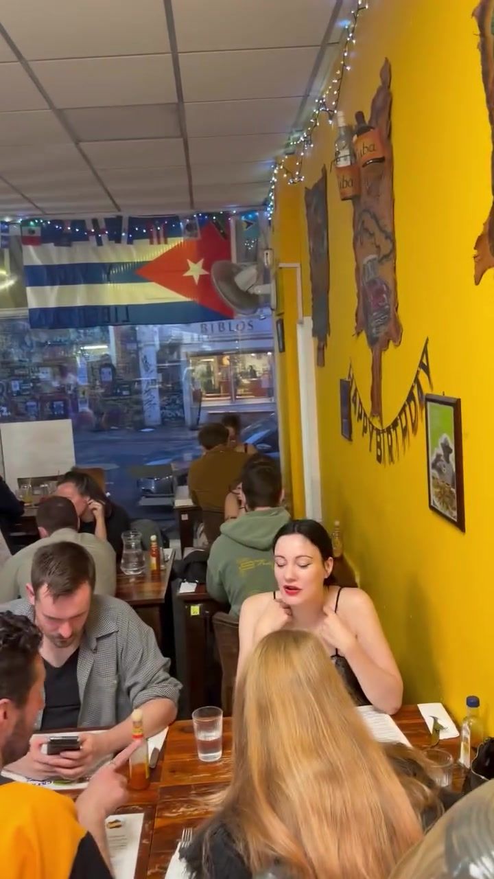 A full dining room at night under the Cuban flag